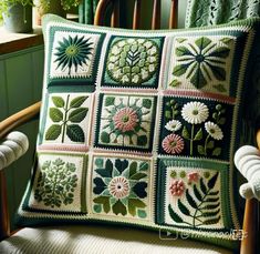 a green cushion with flowers and leaves on it sitting in a chair next to a potted plant