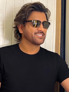 a man with sunglasses on taking a selfie in front of a mirror wearing a black t - shirt