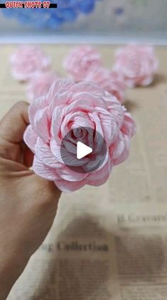 a person is holding some pink flowers in their hand and it looks like they have been made out of tissue paper