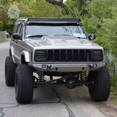 the jeep is parked on the side of the road in front of some bushes and trees