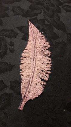 a pink feather laying on top of a black fabric