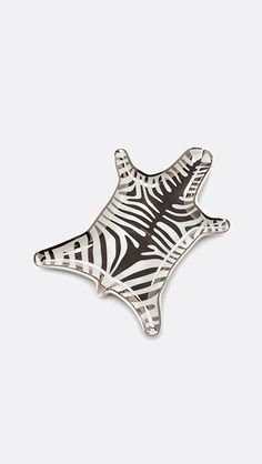 a zebra print pin with black and white stripes on the bottom, in front of a gray background