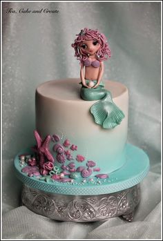 a cake with a little mermaid sitting on top of it