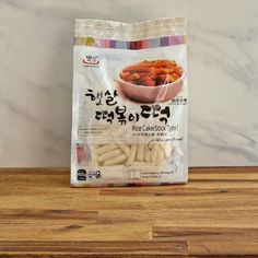 a bag of rice sticks sitting on top of a wooden table next to a bowl