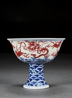 a blue and white bowl with red dragon designs on the bottom, sitting on a gray surface