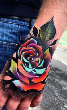 a man's hand with a colorful rose tattoo on it