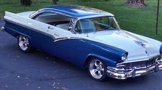 an old blue and white car parked in a driveway