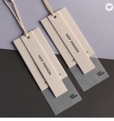 three tags with names on them hanging from strings next to each other in front of a gray background