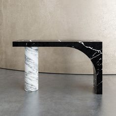 a black and white marble table sitting on top of a cement floor next to a wall