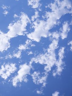 an airplane is flying in the sky with white clouds and blue sky behind it,