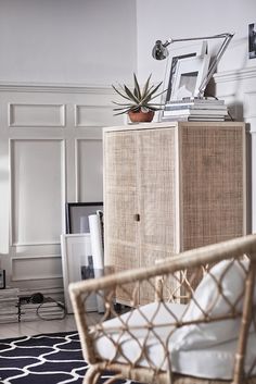 a wicker cabinet in the corner of a living room with a plant on top