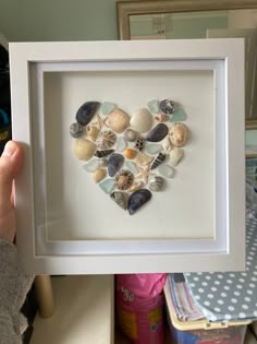 a heart made out of seashells in a white frame