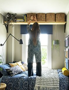 a woman standing on top of a bed next to a window