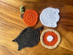 three crocheted pumpkins sitting on top of a wooden table