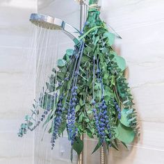 a shower head with water running from it and flowers hanging off the side of it