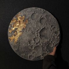 a person holding up a piece of art that looks like the moon