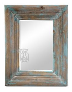 an old wooden frame mirror on a white wall with a blue pattered paint finish