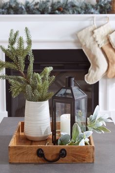 a christmas mantel with candles, potted plants and a lantern