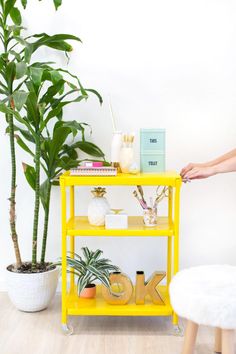 a yellow shelf next to a potted plant