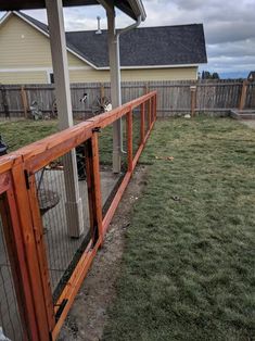 a fenced in area with grass and a dog on the other side of it