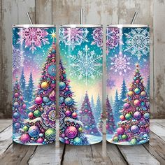 three colorful christmas trees with snowflakes and ornaments on them, sitting in front of a wooden background