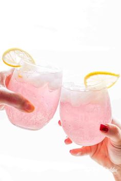 two people holding up glasses filled with pink lemonade