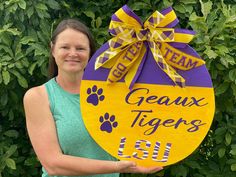 a woman holding up a sign that says geauxx tigers with paw prints on it