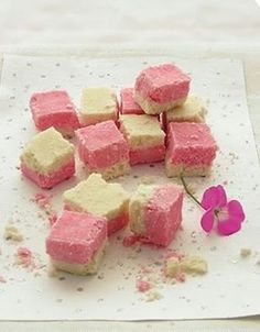 small pieces of pink and white cake sitting on top of a paper towel next to a flower