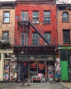 a man walking down the street in front of an apartment building with graffiti all over it