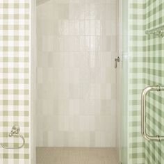 a bathroom with green and white checkered tile on the walls, shower door and toilet