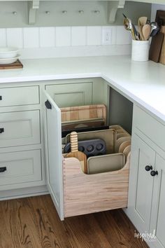 a kitchen with white cabinets and drawers filled with utensils in the drawer space