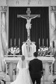 the bride and groom are sitting at the alter in front of the crucifix