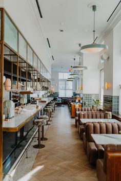 an empty restaurant with long tables and chairs in front of the counter, along with lots of windows