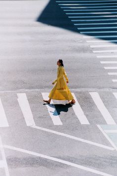 a woman in a yellow dress is crossing the street