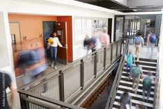 many people are walking up and down the stairs in an office building with orange walls