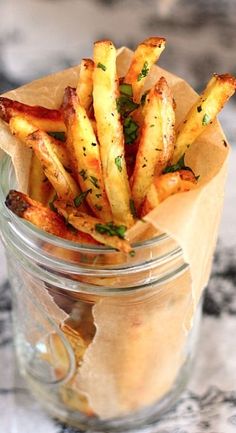 a glass jar filled with french fries on top of a table