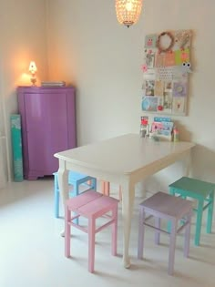 a white table with four chairs and a purple cabinet in the corner next to it