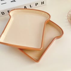 two orange and white dishes sitting on top of a table next to a stack of books