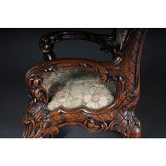 an ornate wooden chair with a floral upholstered seat cushion on it's back