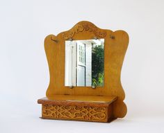 a wooden mirror sitting on top of a table next to a white door and window