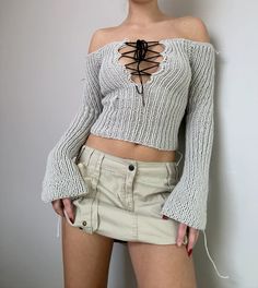 a woman in short shorts and a sweater with a spider on her shoulder is posing for the camera