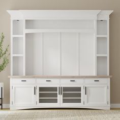 a white entertainment center with built in shelving unit and vase on the floor next to it