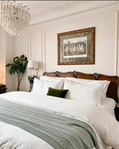 a bedroom with a bed, chandelier and pictures on the wall above it