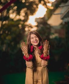 a woman with her hands in the air and flowers on her fingers, smiling at the camera