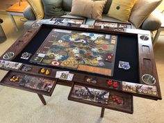 a coffee table with an old board game on it in front of couches and pillows