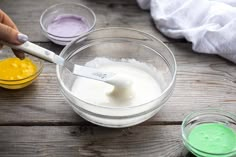 someone is mixing ingredients in a bowl on the wooden table with other bowls and utensils