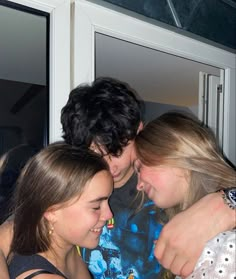 three girls hugging each other in front of a door