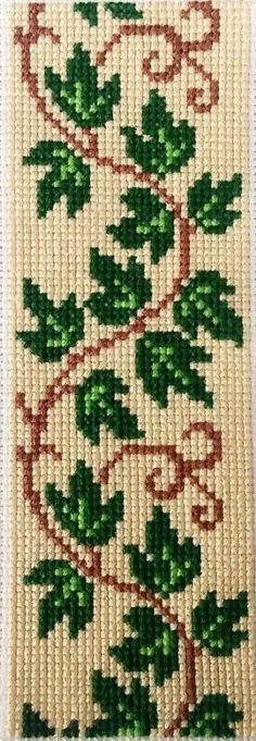 a cross stitch pattern with green leaves and vines on white fabric, in the shape of a tree