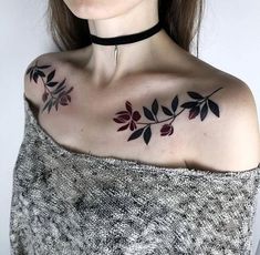 a woman wearing a black choker with red leaves on her chest and shoulder tattoo