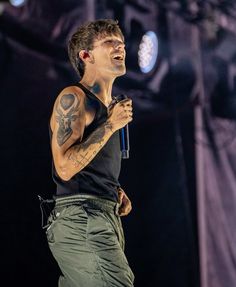 a man with tattoos on his arm holding a microphone